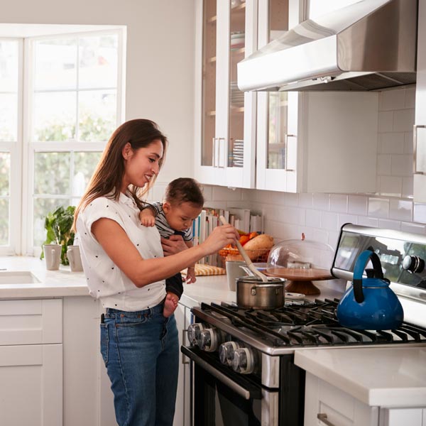 woman holding baby and cooking on gas stove